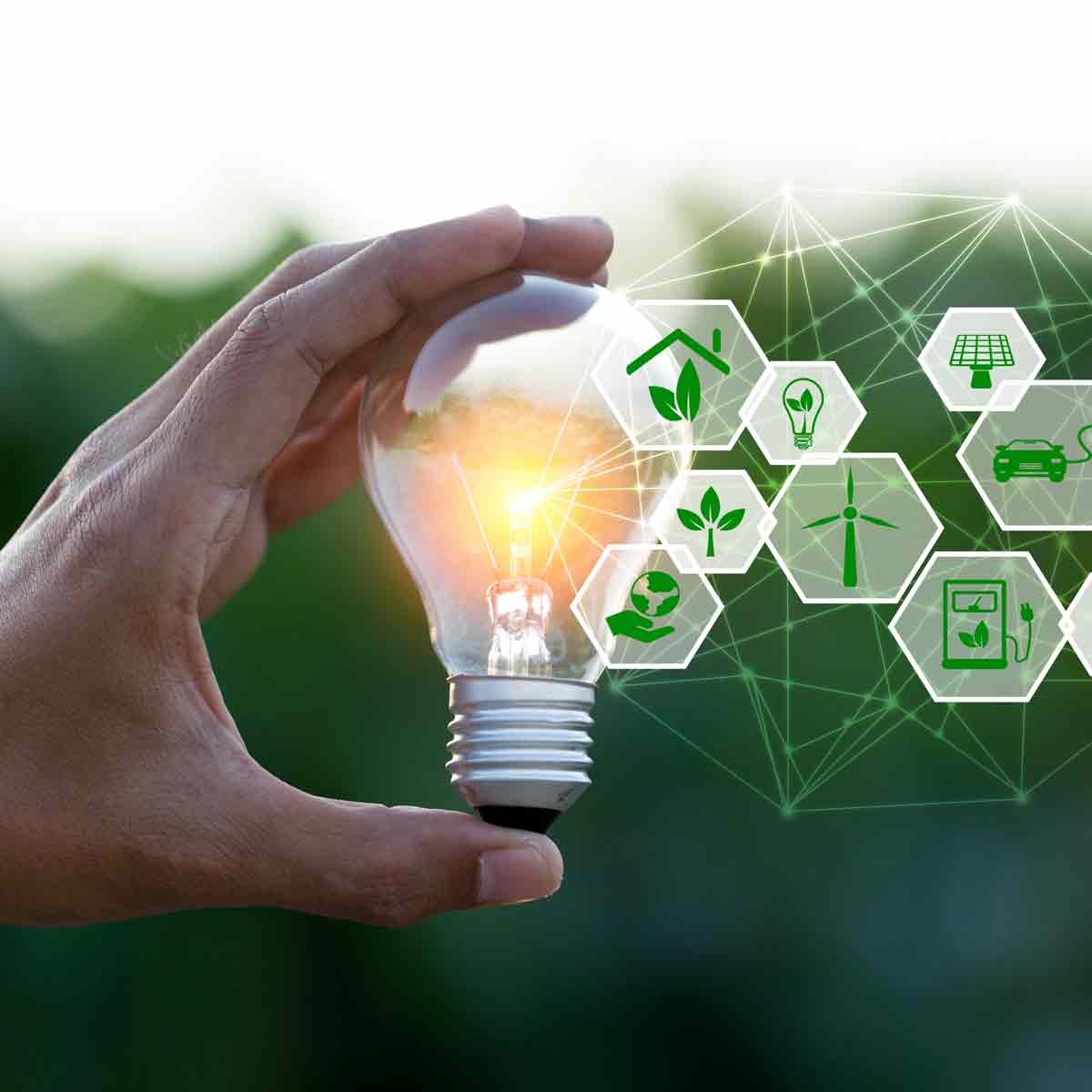 Mano che tiene una lampadina accesa con icone grafiche che rappresentano energia sostenibile e innovazioni tecnologiche.